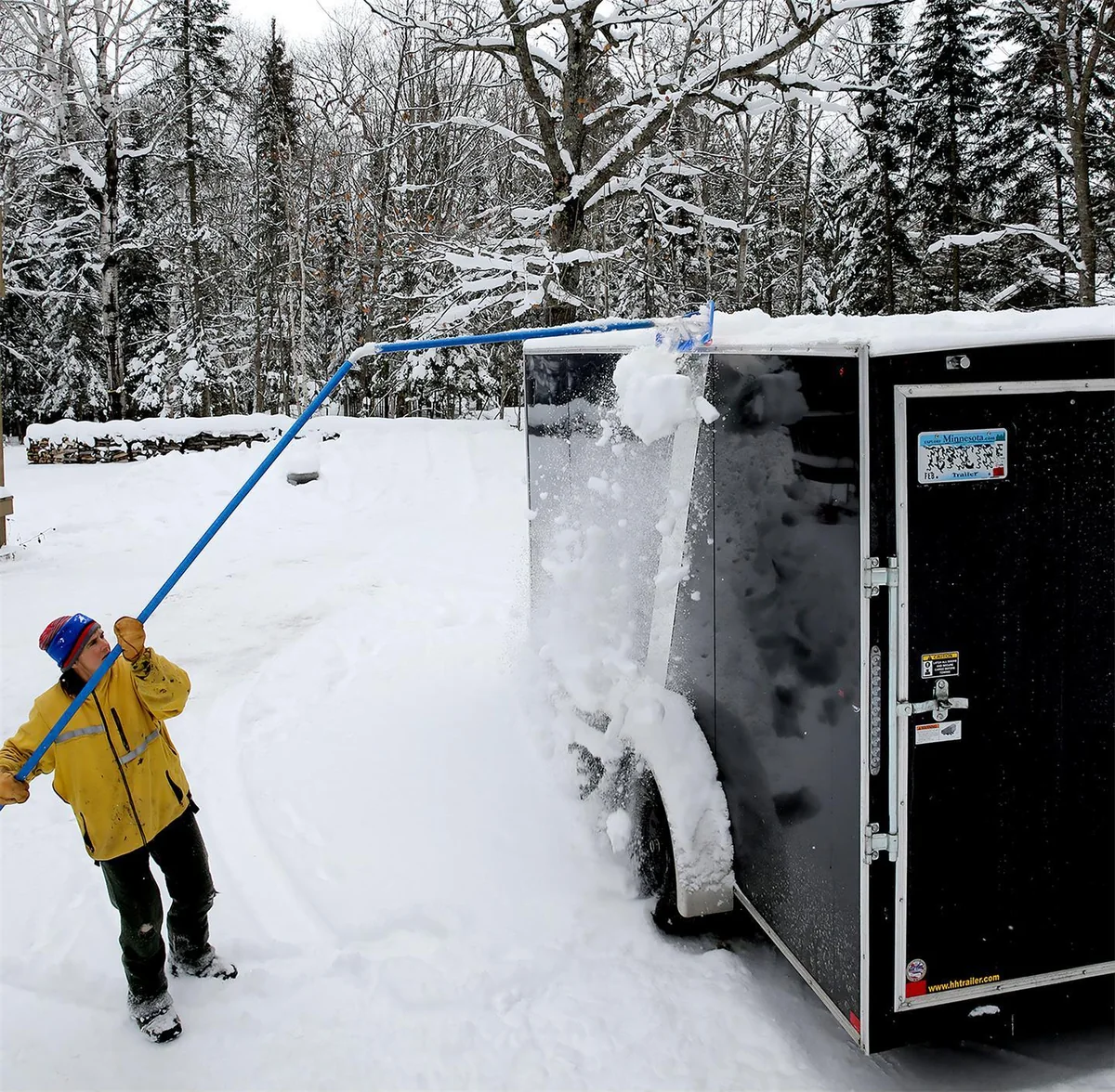 Worker using a MARSHALLTOWN Big Rig Rake to remove accumulated snow from a trailer roof