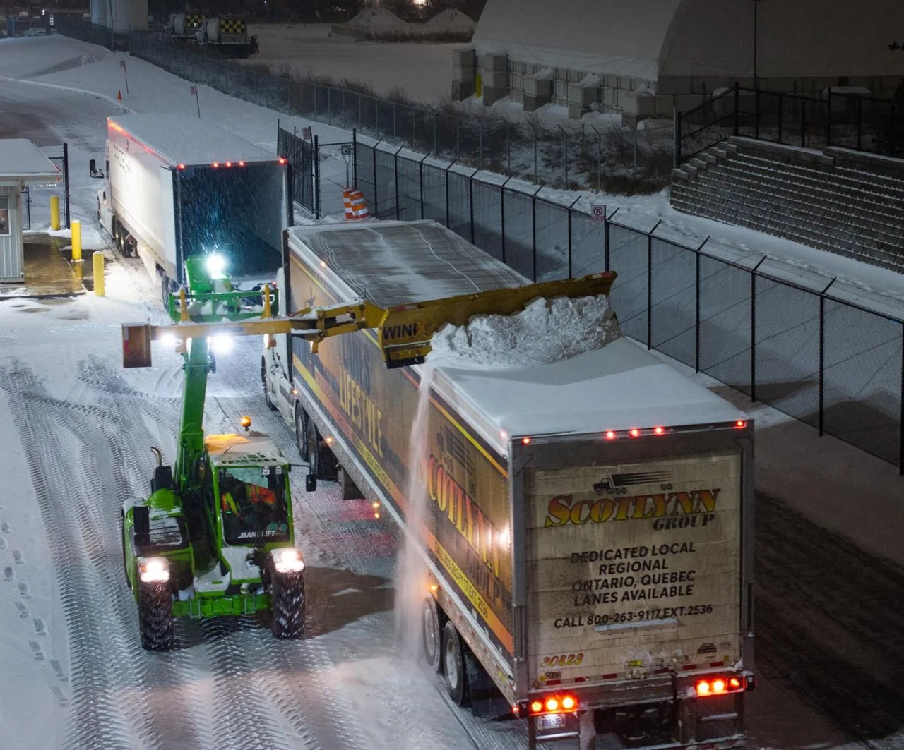 Telehandler using the Rockland SnowEdge to clear accumulated snow from commercial trailer roofs
